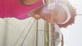 Video of african american female tennis player holding racket and looking at camera. professional tennis training, sport and competition concept.