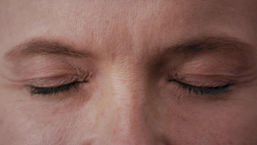 Close up of female face. Adult woman opening her beautiful blue eyes with long eyelashes and smiling. Facial wrinkles,crows feet. Highly detailed portrait of human eyes. Royalty-Free Stock Footage #1091917287