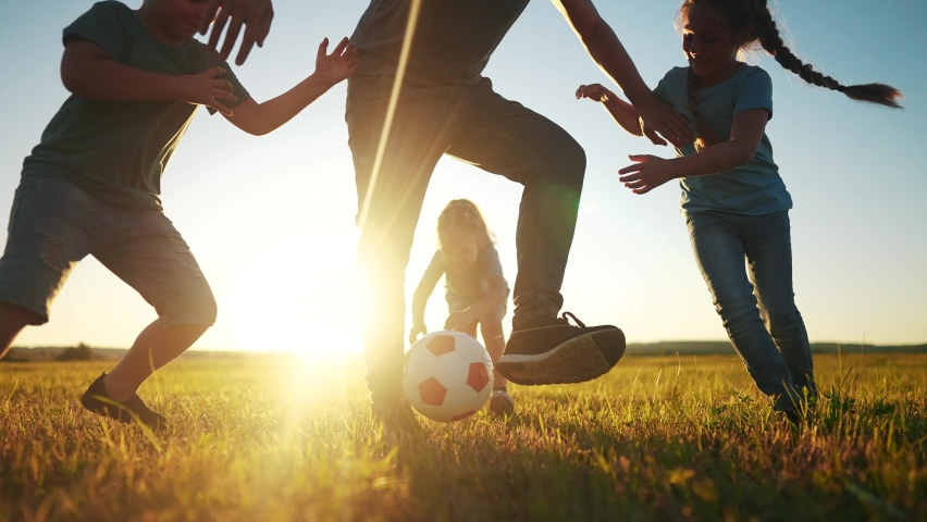 Happy family playing a soccer in the park. group of children in nature playing ball with father silhouette park. happy family kid dream concept. funny kids playing ball on the grass in summer sunlight | Shutterstock HD Video #1091918787