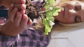 Video of happy caucasian woman holding seedling. modern organic farm, agriculture business and technology concept.