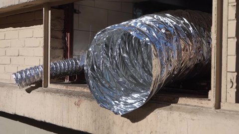 Flexible aluminum foil duct at the window. corrugated exhaust hose
