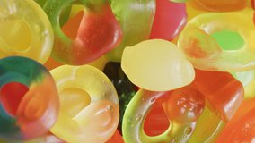 Video of multicoloured lollipops on yellow background. colourful fun food, candy, snacks and sweets concept.