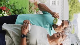 Video of relaxed biracial senior couple drinking coffee in garden. active retirement lifestyle, senior relationship and spending time together.
