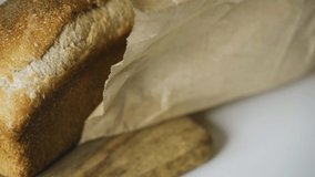 Homemade bread in a paper bag lying on the kitchen board. Camera movement from right to left. Close-up