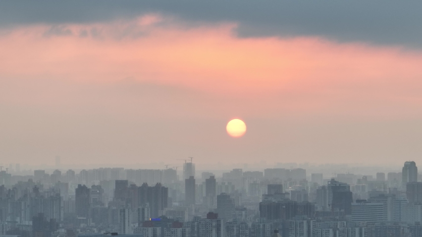 Drone aerial view of City in the dusk and the orange sunset glow. Flying over the city with rows of buildings, beautiful sunset Shanghai China. Business, travel and life style concept b-roll footage.