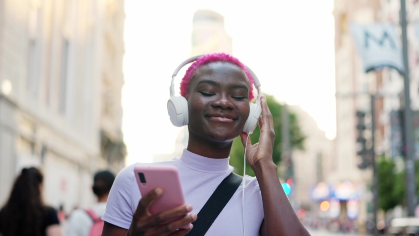 Smiling woman listening to music and dancing in the street | Shutterstock HD Video #1091926353