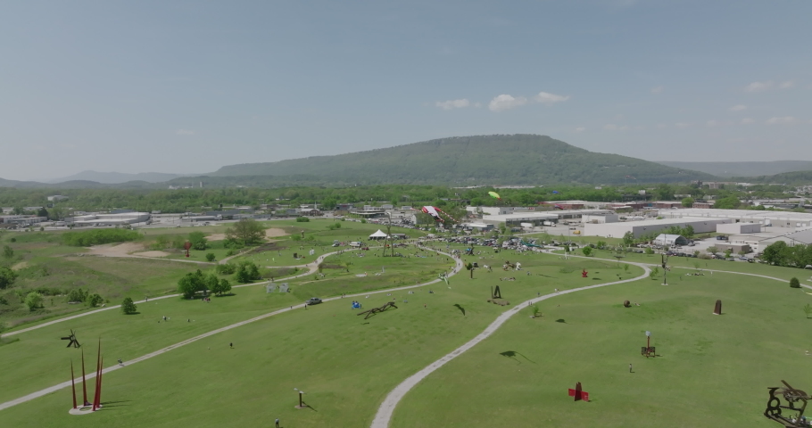 Aerial flyover of a kite festival in The Sculpture Fields with Lookout Mountain in the background in Chattanooga, TN.