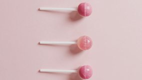 Video of pink lollipops on pink background. colourful fun food, candy, snacks and sweets concept.