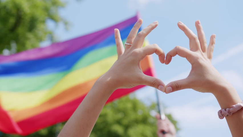 Hands Make Heart Sign Supporting Lgbt Community In Front Of Flying Rainbow Flags And Blue Sky, Protest Signs On Gay Pride Parade March Celebration Event Symbol Of LGBT GLBT Love Equal, Diversity