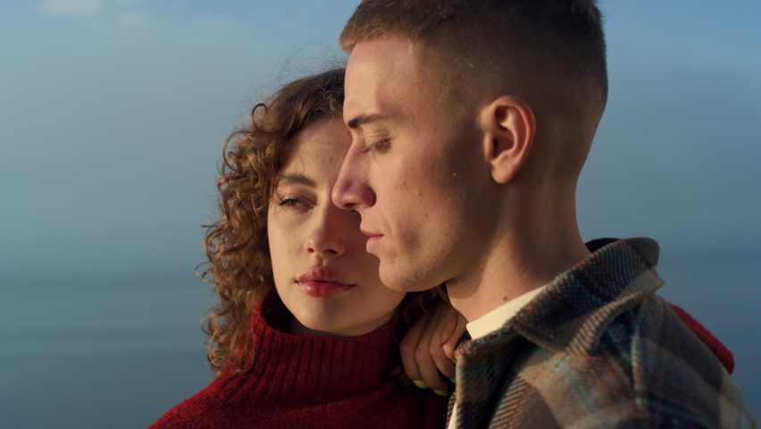 Closeup cheerful couple looking at camera. Fashion woman and man posing on sea background. Young people with serious face expression. Female and male models wearing casual clothes. Youth concept