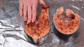 Raw salmon Fillet or red fish steak. Seasoning salmon steak. Girl spreads ground pepper and olive oil on raw salmon steak before baking. High quality FullHD footage