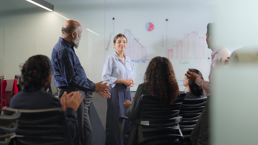 Modern confident attractive Young Indian Asian corporate woman or female millennial giving a presentation or communicating with office colleagues using white board graphs in formal conference setup. Royalty-Free Stock Footage #1091942461