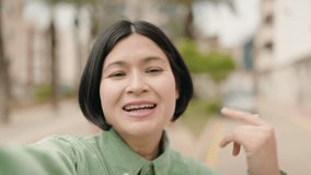 Young chinese woman smiling confident having video call at street