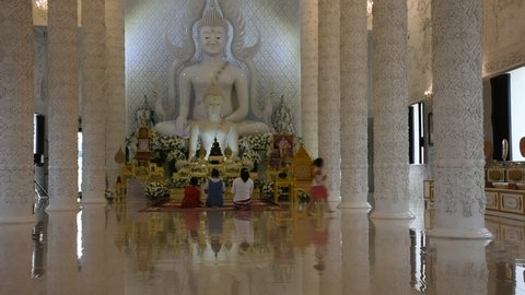 Thai people and foreign travelers travel visit and respect praying beautiful white buddha statue in ubosot church at Wat Rong Seur Ten or artistic blue temple on June 30, 2022 in Chiang Rai, Thailand