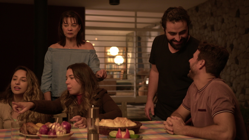 Family and friends at night together around table in backyard in conversation talking and lauging