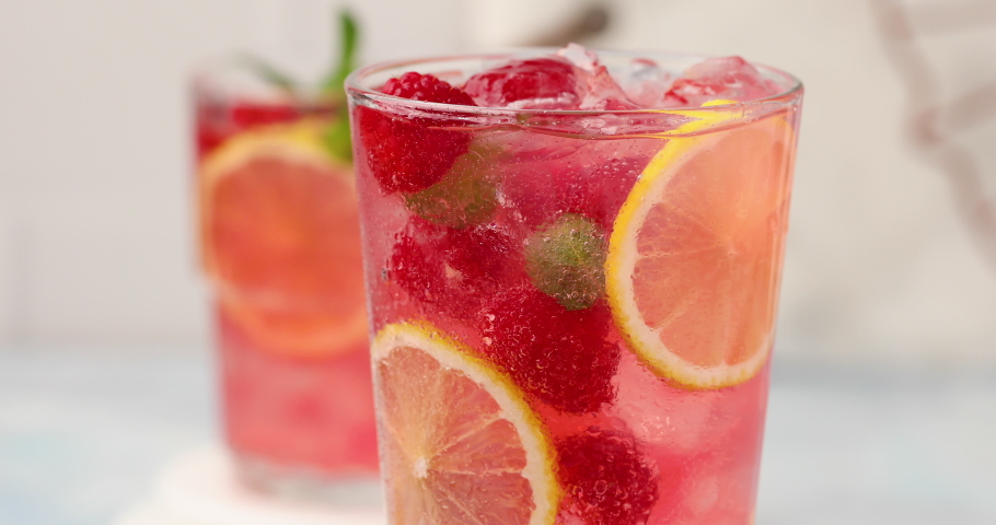 Cold and refreshing summer cocktail with raspberry and lemon on ice being stirred with a spoon close up Royalty-Free Stock Footage #1091949971