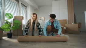 Cheerful young couple in their new apartment, rolling out carpet. Conception of moving. - Powered by Shutterstock - Get 15% off with code: PIKWIZARD15
