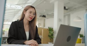 Young confident and cheerful asian business woman online conference with co-worker. Female freelancer entrepreneur speaking looking at laptop computer virtual training in distance office chat meeting.