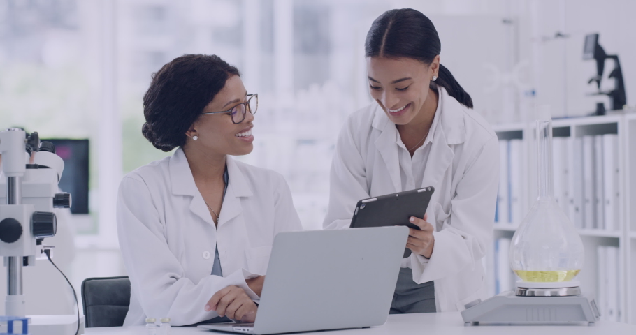 Two scientists high five while using a digital tablet in a laboratory. Happy female doctors celebrate an achievement after making a scientific discovery. Successful research results in advanced lab Royalty-Free Stock Footage #1091954279