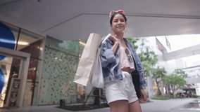 Low Angle Shot on a Confident Stylish Woman Enjoys shopping, walking on street shops against a modern community mall in middle of city. Reopening Shops, Big Sale Promotion after covid-19 pandemic. - Powered by Shutterstock - Get 15% off with code: PIKWIZARD15