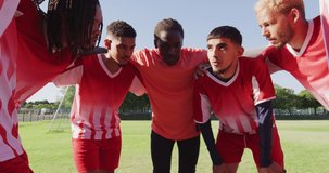 Video of diverse group of male football players on field,discussing game tactics. Male football team, inclusivity and fitness in team sports.
