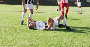 Video of two diverse footballers helping fouled teammate. Male football team, inclusivity and fitness in team sports.