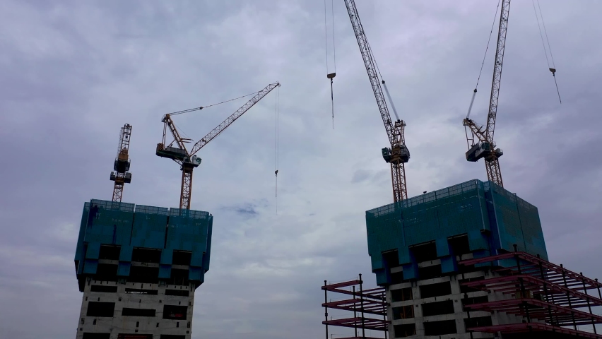 Close up aerial view of crane lowering an object on the roof of the skyscraper under construction in Jakarta, Indonesia | Shutterstock HD Video #1091979245