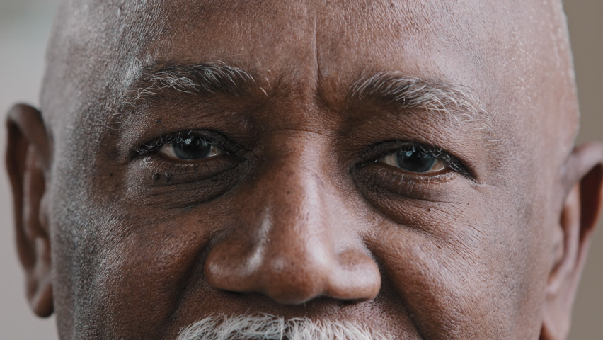 Close-up male dark eyes wrinkled face African American old man looking at camera with sad expression elderly senior man poor vision trouble eyesight problem ophthalmology insurance health care service