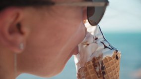a girl eats ice cream in a cone on the beach. a girl goes with an ice cream cone on the beach. close-up of lips with chocolate ice cream. hot summer. melted ice cream flows down the arm - Powered by Shutterstock - Get 15% off with code: PIKWIZARD15