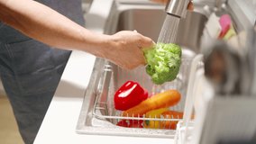 Asian senior man washing and cleaning vegetables in the kitchen sink - Powered by Shutterstock - Get 15% off with code: PIKWIZARD15