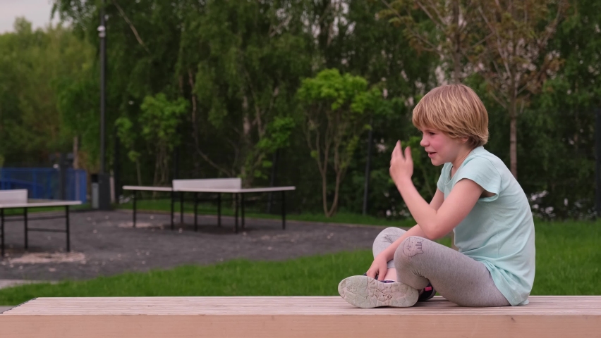 Tired child sits on a bench. The boy