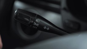 A man turns on the turn signal to the left on the lever in the car. Automotive panel close-up. - Powered by Shutterstock - Get 15% off with code: PIKWIZARD15