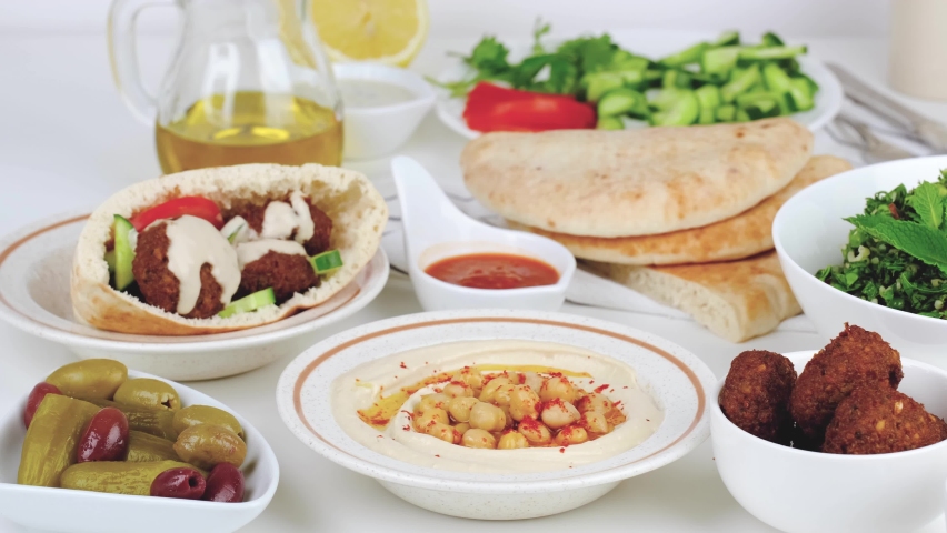 Israeli breakfast on a table. Hummus, pita, falafel, tabouleh, olives and vegetables.