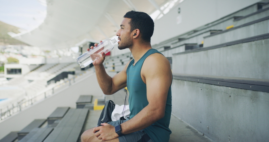 Fit, active, sporty and athletic man staying hydrated and accomplishing fitness goals. Thirsty male athlete drinking water from a bottle and smiling after workout training exercise in sports stadium Royalty-Free Stock Footage #1091995967