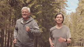 Medium slowmo of cheerful mature couple jogging together along forest trail on sunny day - Powered by Shutterstock - Get 15% off with code: PIKWIZARD15