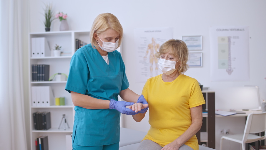 Therapist in face mask examining senior female patient hand, arthritis treatment Royalty-Free Stock Footage #1092005387
