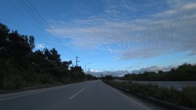 OKINAWA, JAPAN - AUGUST 2021 : Driving shot of Okinawa in sunset time. Point of view (POV), seaside road drive. Summer holiday, vacation and travel concept video.