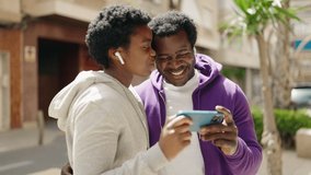 African american man and woman couple watching video on smartphone at street