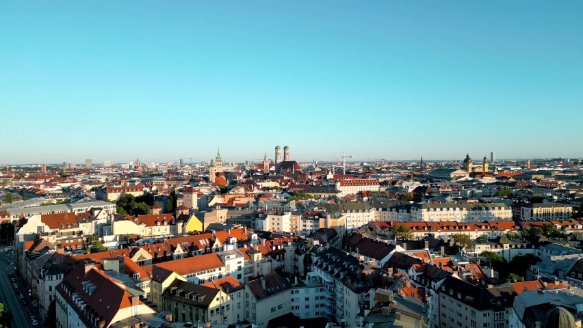 Panorama aerial view Munich downtown sunrise. Drone flies over residential area of central bavarian capital, Frauenkirche, Marienplatz and other landmarks in background. Stunning aerial city view