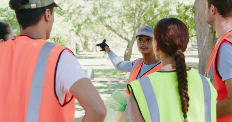 Group of diverse smiling community workers uniting for a cleanup service or project outdoors. Young happy volunteers talk before collecting trash in a park for recycling to keep nature healthy Royalty-Free Stock Footage #1092012843