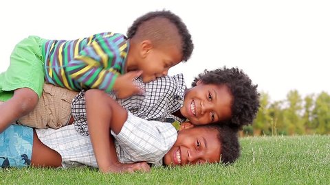 Black boy playing on the green grass. Three fun brother.