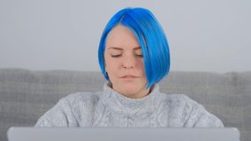 Ukrainian woman working on laptop. Portrait of blue haired white female doing distant work on notebook pc. Young programmer coding on computer at home in 4k stock video clip. Freelancer person works