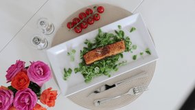 Close-up of a slow-motion shot of grilled fish. Salmon in a white plate with vegetables and green ingredients. The concept of healthy seafood and proper nutrition