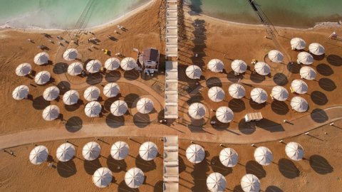 Bird's eye view, aerial footage of the Dead Sea beach with bathers floating in the salty water.