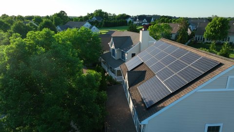 Rooftop solar panels on home in American neighborhood. Sun reflects light. Green renewable energy theme. Aerial. Stock Video