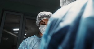 Close-up of a surgeon's face bent over a patient during surgery. Teamwork of medical personnel for surgical intervention in a modern operating room. Video in 4k, red komodo