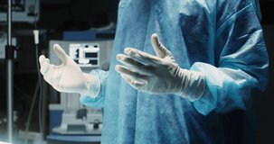 An African-American surgeon dressed in a medical gown and sterile gloves, with a disposable mask and cap on his head, is ready for surgery, video motion from hand to face. Video in 4k, red komodo