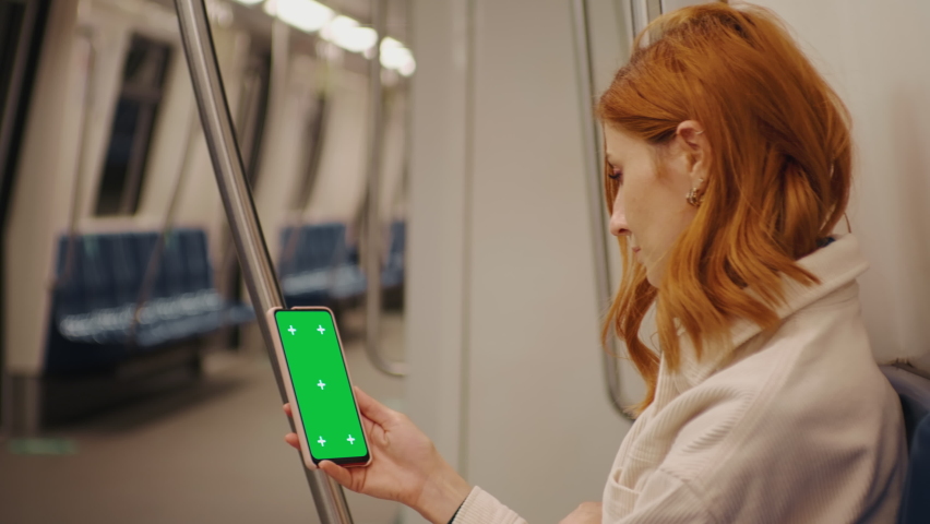 Side view female watching green screen phone in the subway train. Social Network. Work and Travel. New Apps. Phone User. Smartphone with Green Screen Mock Up Display. | Shutterstock HD Video #1092028225