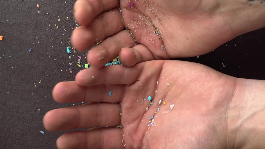 Close-up on micro plastic particles falling in person's hand. Concept for water pollution and global warming. Macro shot on a bunch of microplastics that cannot be recycled | Shutterstock HD Video #1092030991