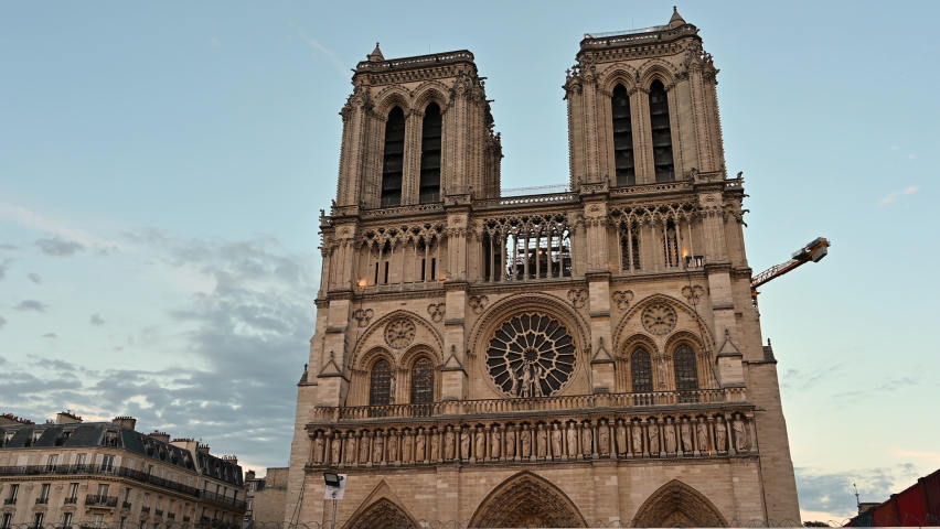 Paris, France. June 2022. Nice evening footage of the notre dame facade. The crane of the restoration site can be seen after the great fire that damaged the cathedral. Pan movement. Royalty-Free Stock Footage #1092032143